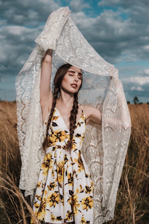Free Woman in sunflower dress holding up lace fabric Stock Photo