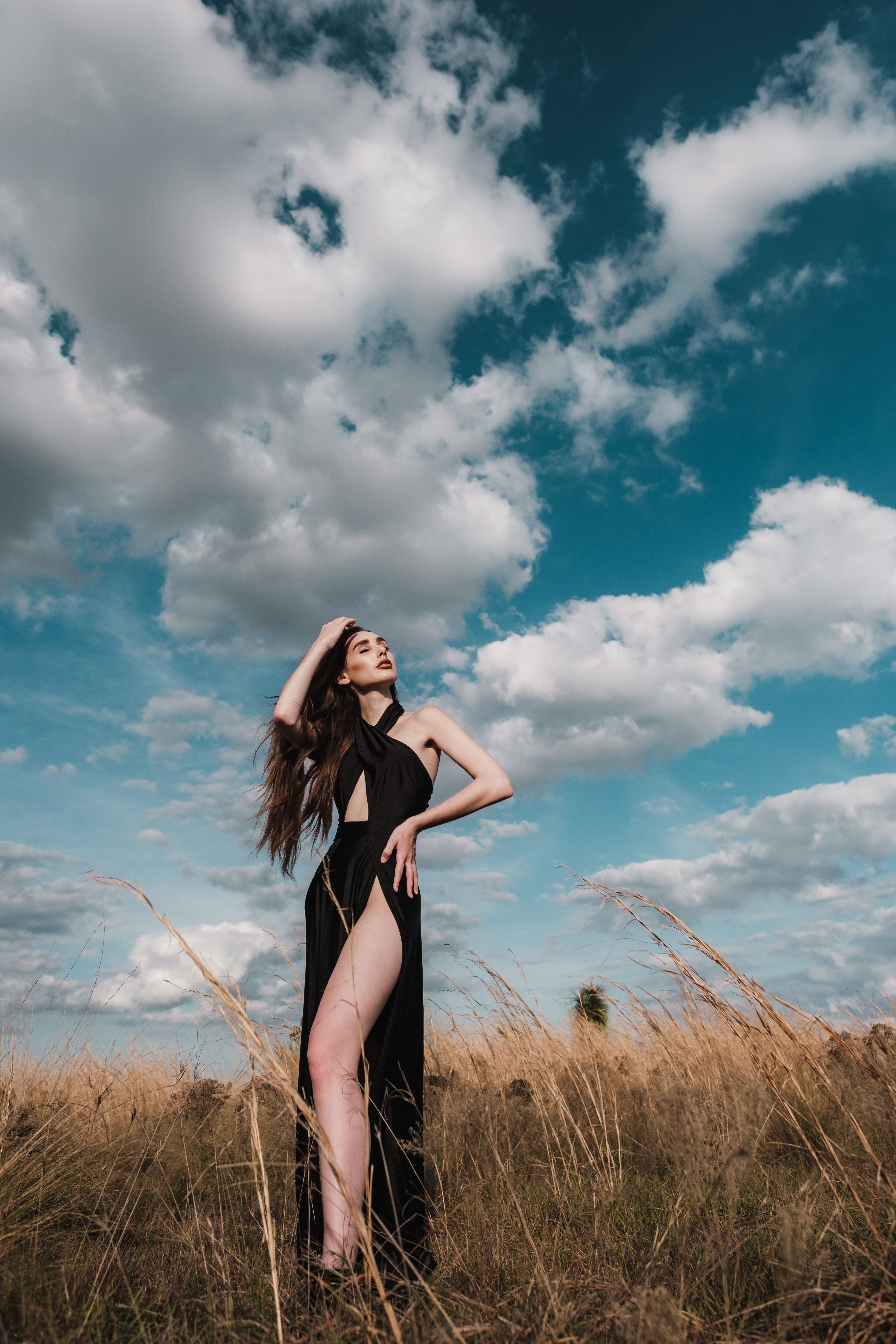 A striking image of a woman posing in a field under a dramatic cloudy sky in Orlando.