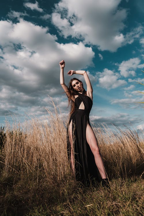Woman in Black Sleeveless Dress Standing on a Grass
