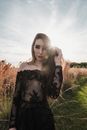 Woman in Black and Brown Floral Long Sleeve Shirt Standing on Brown Grass Field