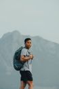 Man in Green Jacket and Black Backpack Standing on Mountain