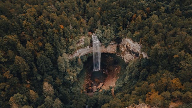 Stunning aerial shot of a waterfall surrounded by lush green forest in Pikeville, Tennessee.