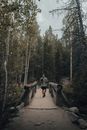 Man and Woman Walking on Bridge Surrounded by Trees