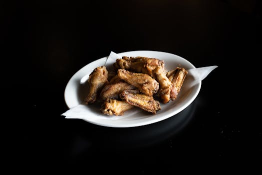 Close-up of crispy fried chicken wings on a white plate, perfect for food presentations.