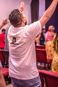A man raising his hands in prayer during a church service, expressing devotion.