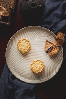 Artistic vertical shot of mooncakes on a textured plate with tea, dark tones enhancing the ambiance.