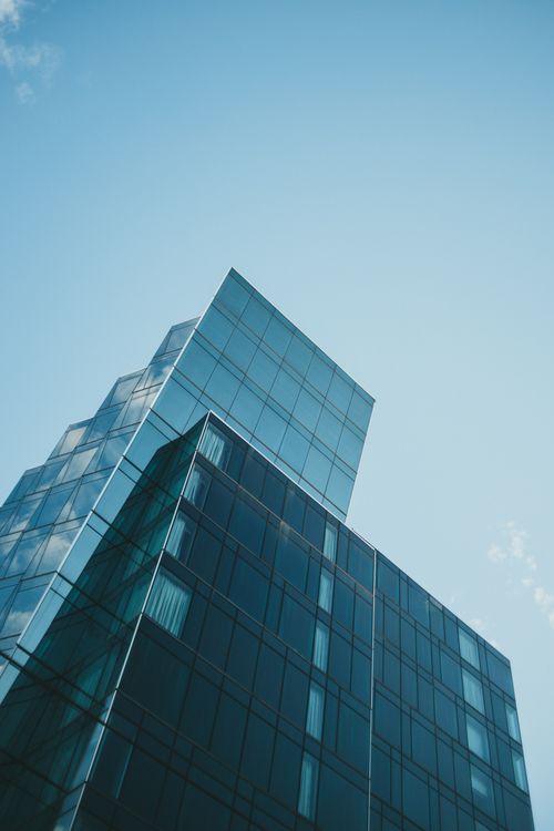 Free Contemporary glass skyscraper reaching into the clear blue sky, showcasing modern architectural design. Stock Photo