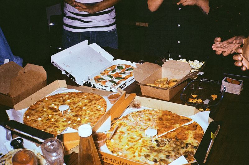 Open pizza boxes arranged on a wooden party table