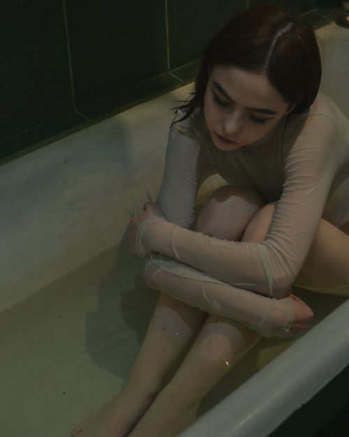 Free A pensive woman in translucent attire reflects quietly while sitting in a bathtub. Stock Photo