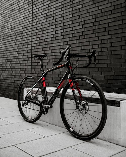 Red and Black Bike Parked Near Brick Wall