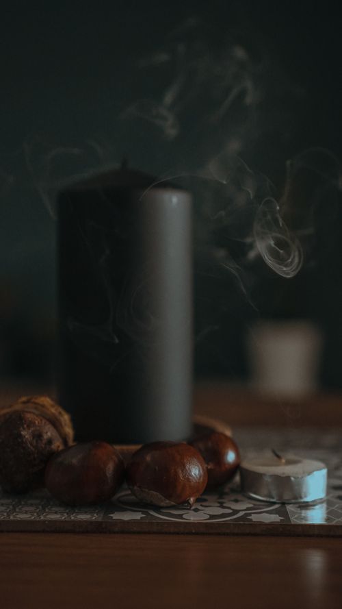 Free Dark candle surrounded by chestnuts with smoke in a cozy autumn atmosphere. Stock Photo