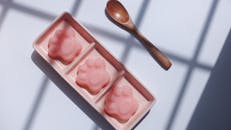 粉色托盘上放着三个可爱的爪子形果冻，配有木勺，非常适合甜点爱好者