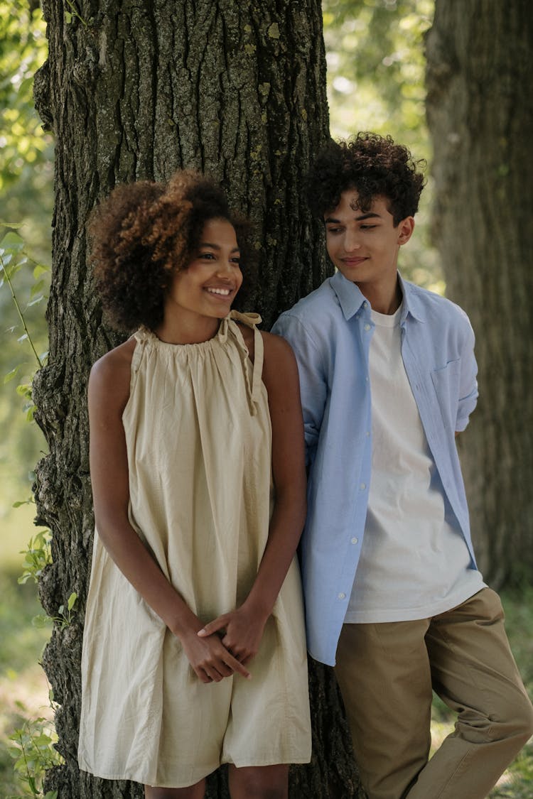 A Boy And Girl Leaning On A Tree