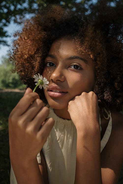 A Girl with Afro Hair Holding a Flower