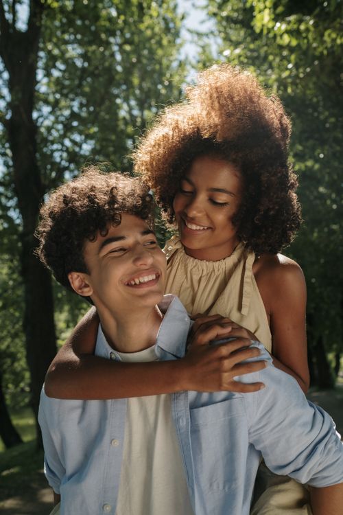 Free A couple sharing a joyful moment in a sunlit park, symbolizing young love and happiness. Stock Photo