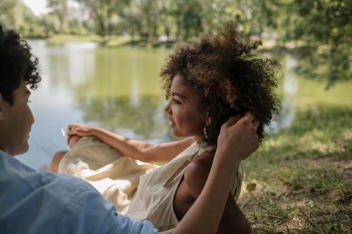 Free A serene moment of a couple enjoying nature by a lake, capturing romance and tranquility. Stock Photo