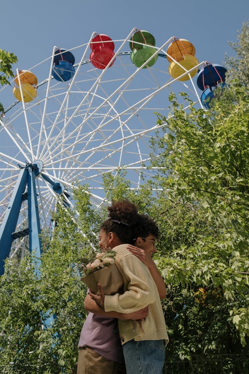 Teenage couple hugging under ferris wheel