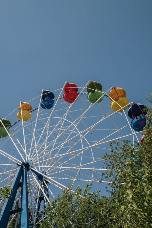 Free A vibrant ferris wheel with colorful gondolas captured on a clear summer day. Low angle view. Stock Photo