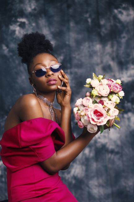 Glamorous woman posing with a bouquet in a vibrant studio fashion shoot.