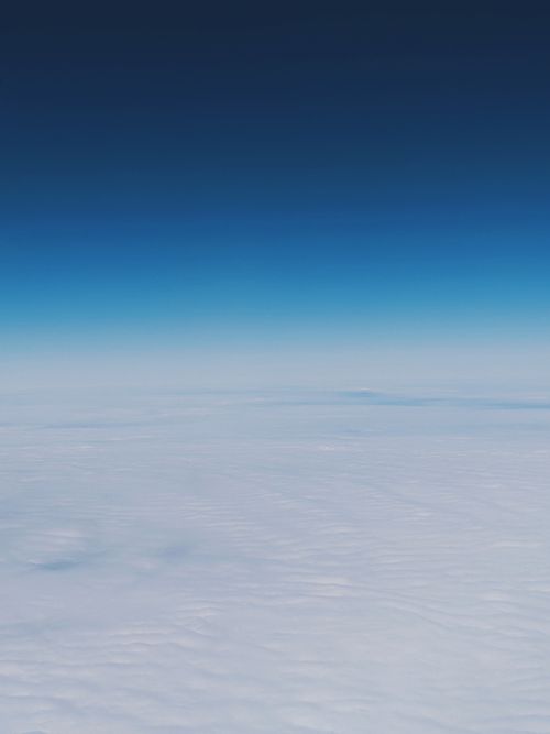 Free Stunning aerial view showcasing a vast sea of clouds beneath a vibrant blue sky. Stock Photo