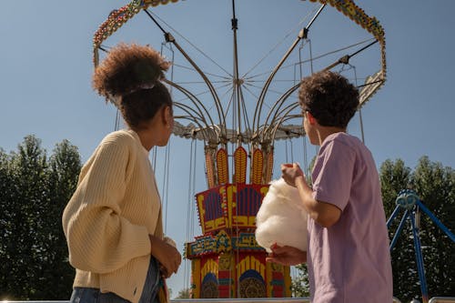 Free Teenage couple on date in amusement park looking at big carousel Stock Photo