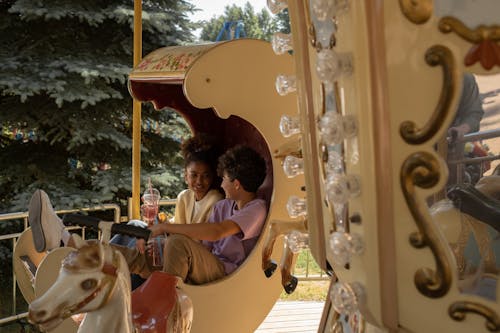 Teenage couple sitting in carousel seat smiling and talking to each other