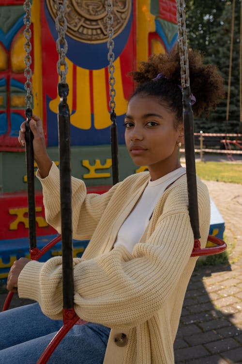 Cute black teenage girl sitting in carousel seat at amusement park