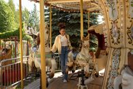 Cheerful teenage girl getting on carousel