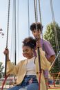 Teenage boy standing behind teenage girl sitting in carousel seat