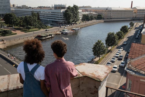 Teenage couple on date standing on rooftop and admiring beautiful view at river and city