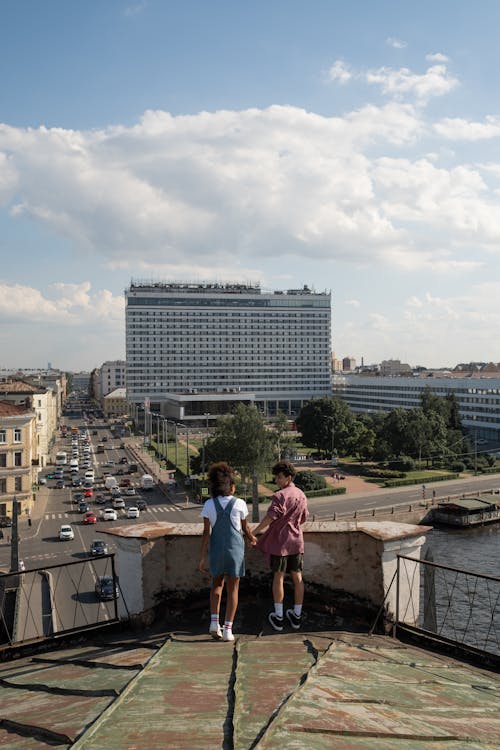 A Couple Holding Hands while Standing on the Rooftop