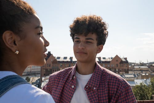 Teenagers standing on rooftop talking and looking at each other