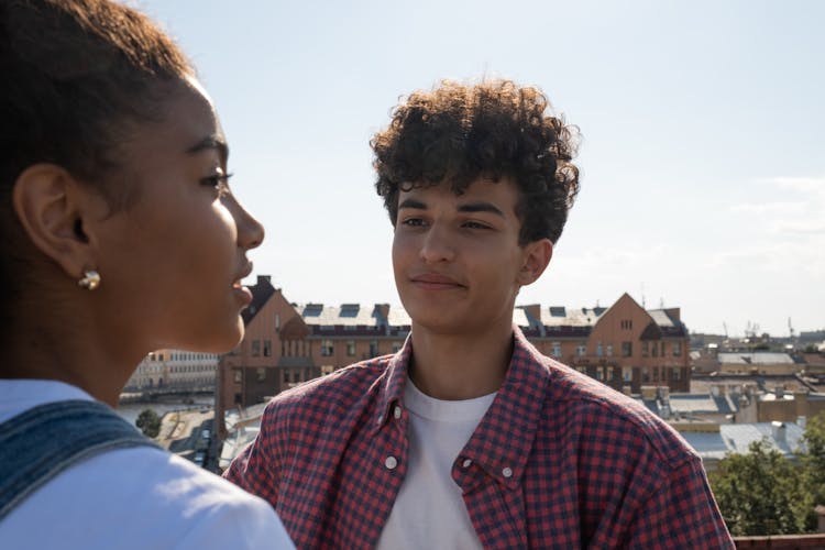 Teenagers Standing On Rooftop Talking And Looking At Each Other