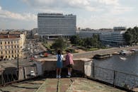 Teenage couple on date standing on rooftop and admiring panorama of river and city