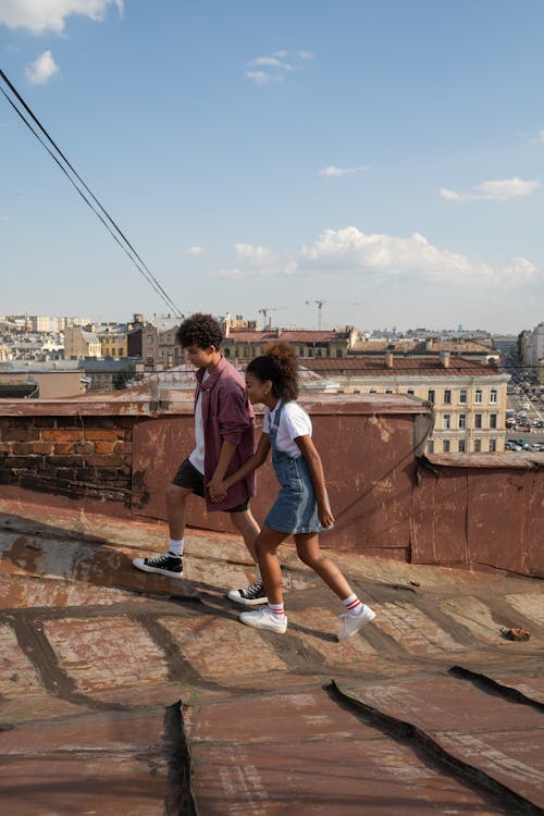 Teenage couple walking holding hands on rooftop