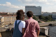 Teenage couple standing on rooftop and looking at river and city