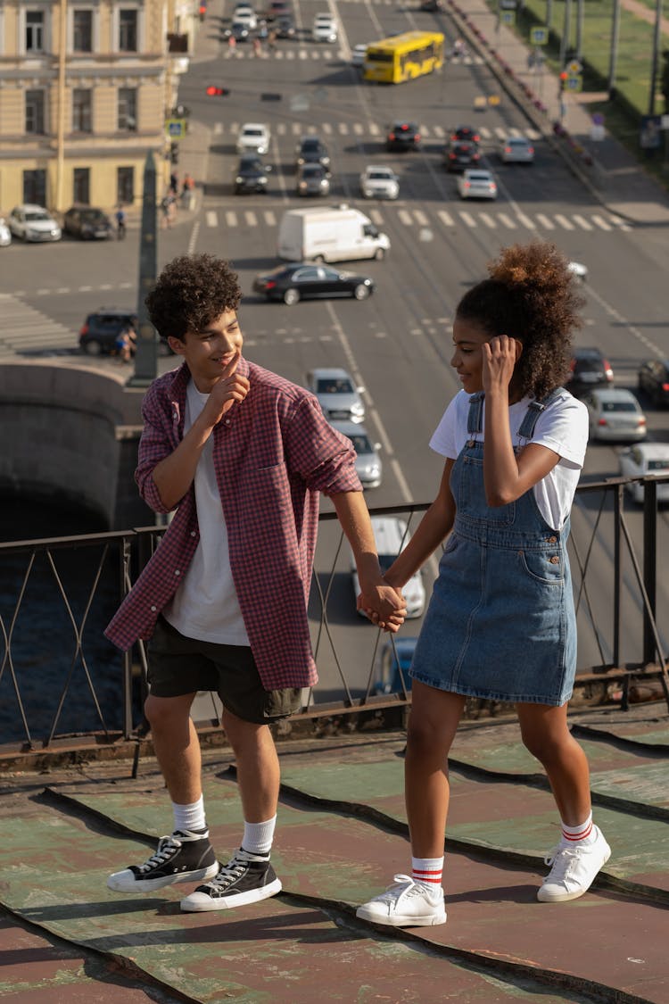 Teenage Couple Walking Holding Hands On Roof