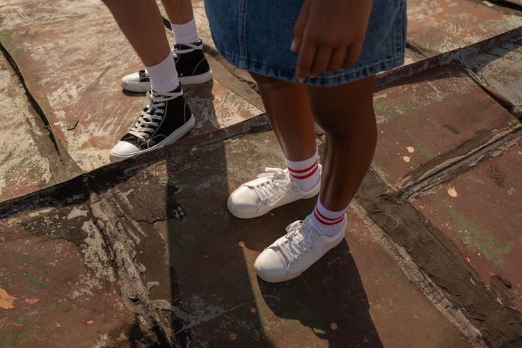 Sneakers On Teenagers Legs Standing On Red Painted Rooftop 