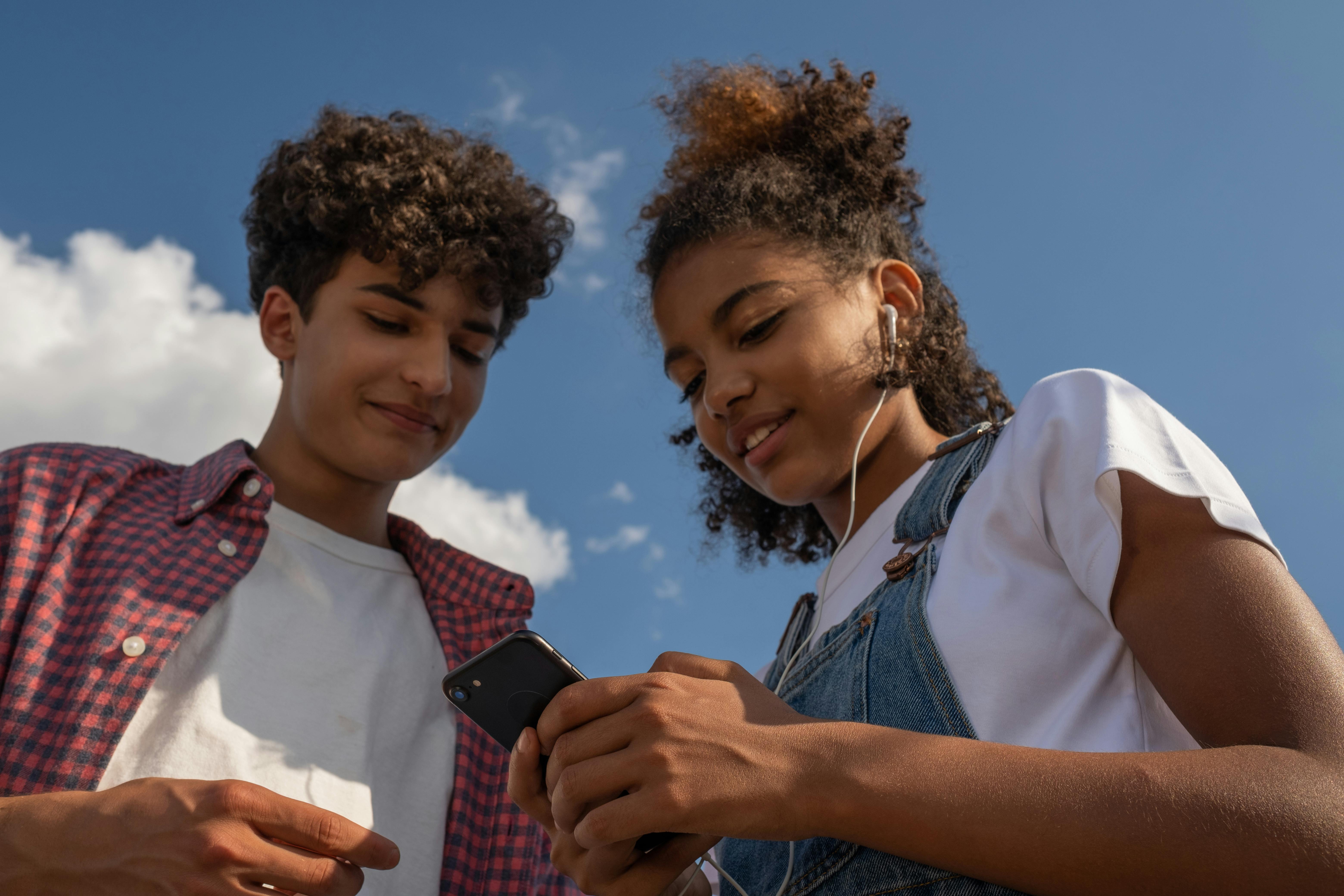 teenagers looking at the screen of a cellphone