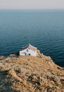 White and Brown Concrete House on Brown Rock Formation Beside Blue Sea