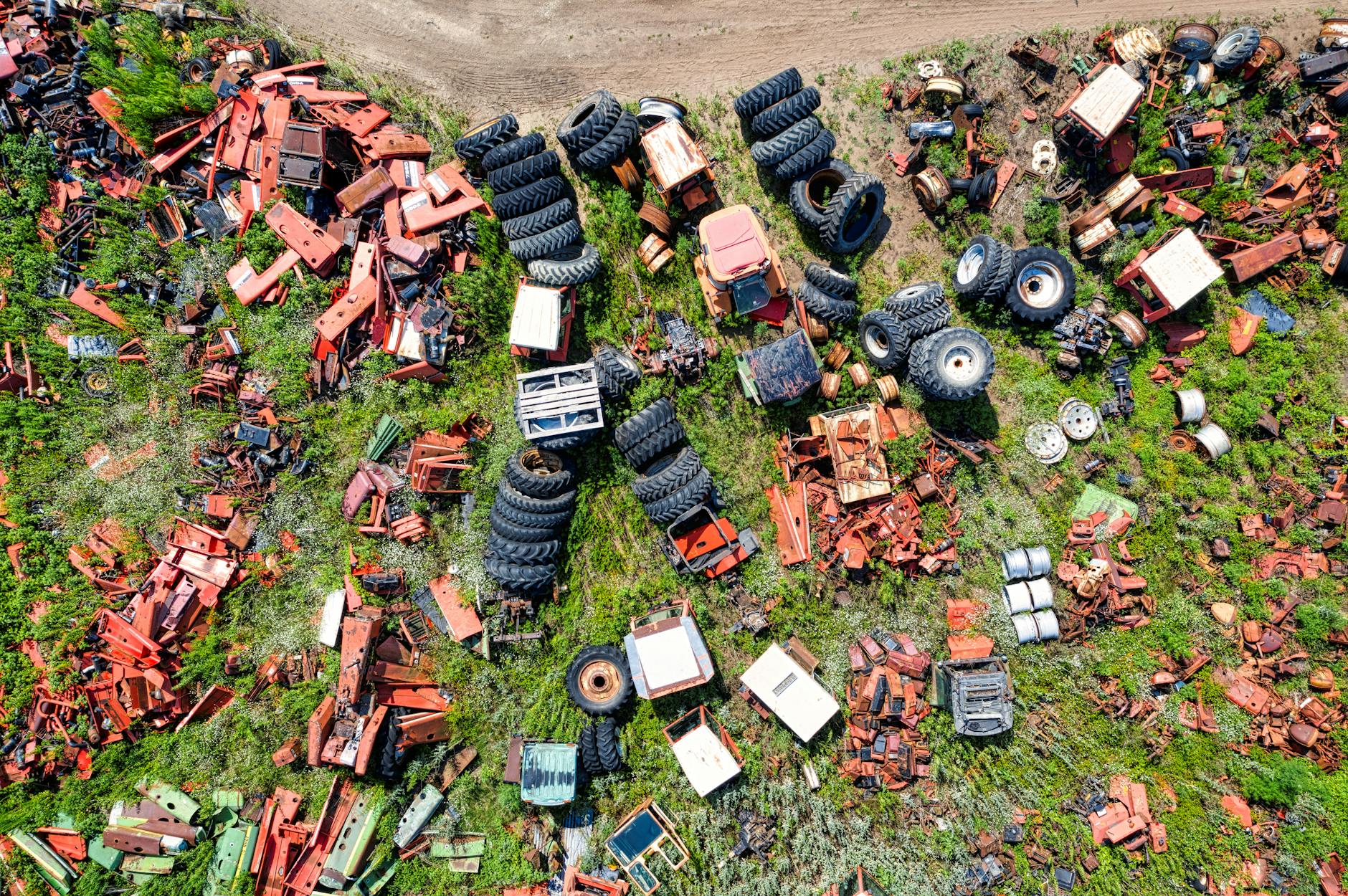 High-angle view of a junkyard filled with scrap metal and scattered tires in an outdoor setting.