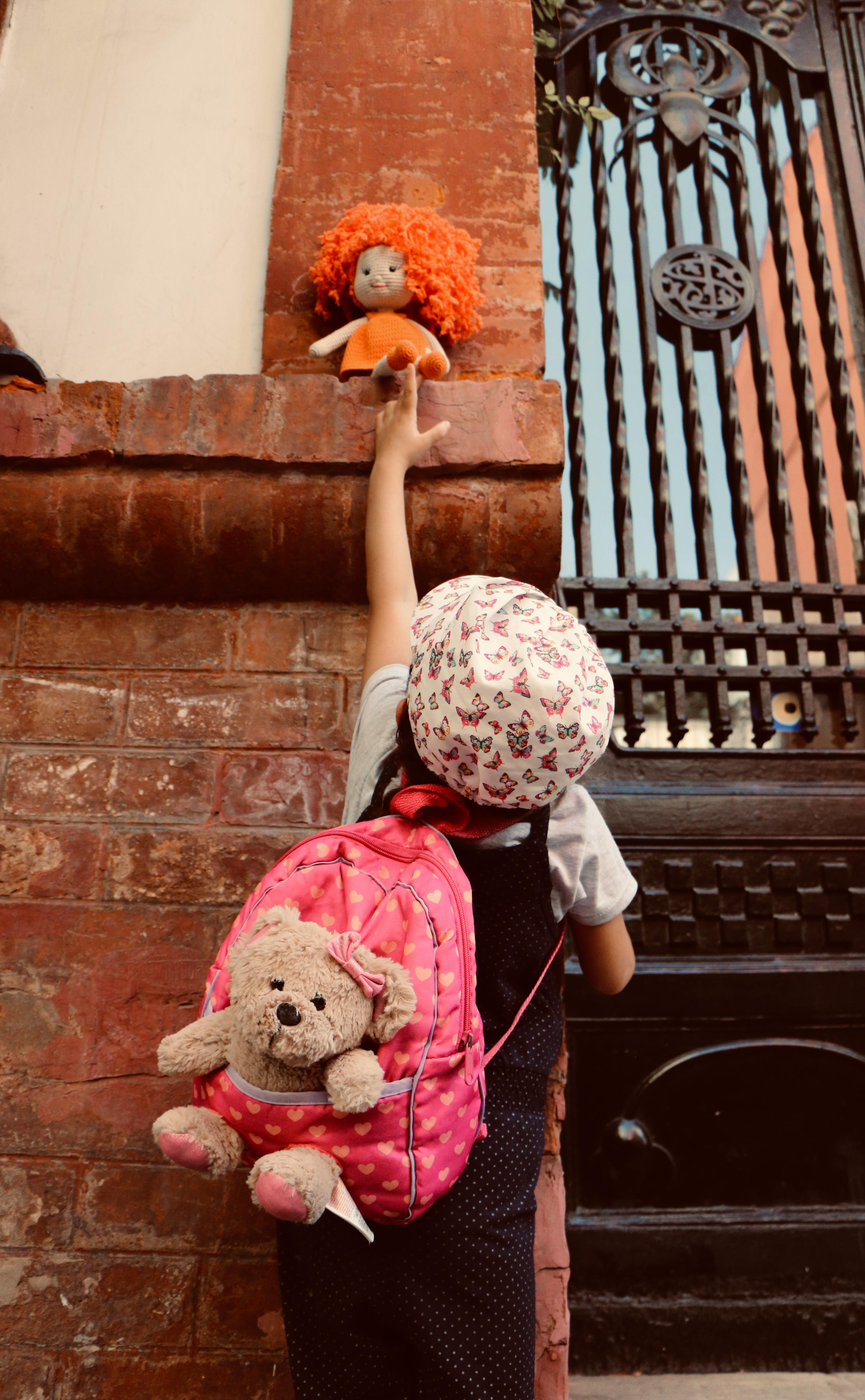 a young girl getting a doll on the concrete wall