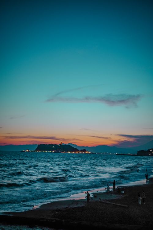 Free A tranquil beach setting at twilight with gentle waves and a distant island silhouette. Perfect for travel and nature themes. Stock Photo