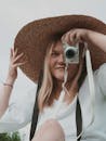 Woman in White Shirt Wearing Brown Straw Hat Holding Camera