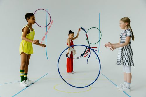Free A fun indoor scene with diverse kids playing with colorful hula hoops, emphasizing play and friendship. Stock Photo
