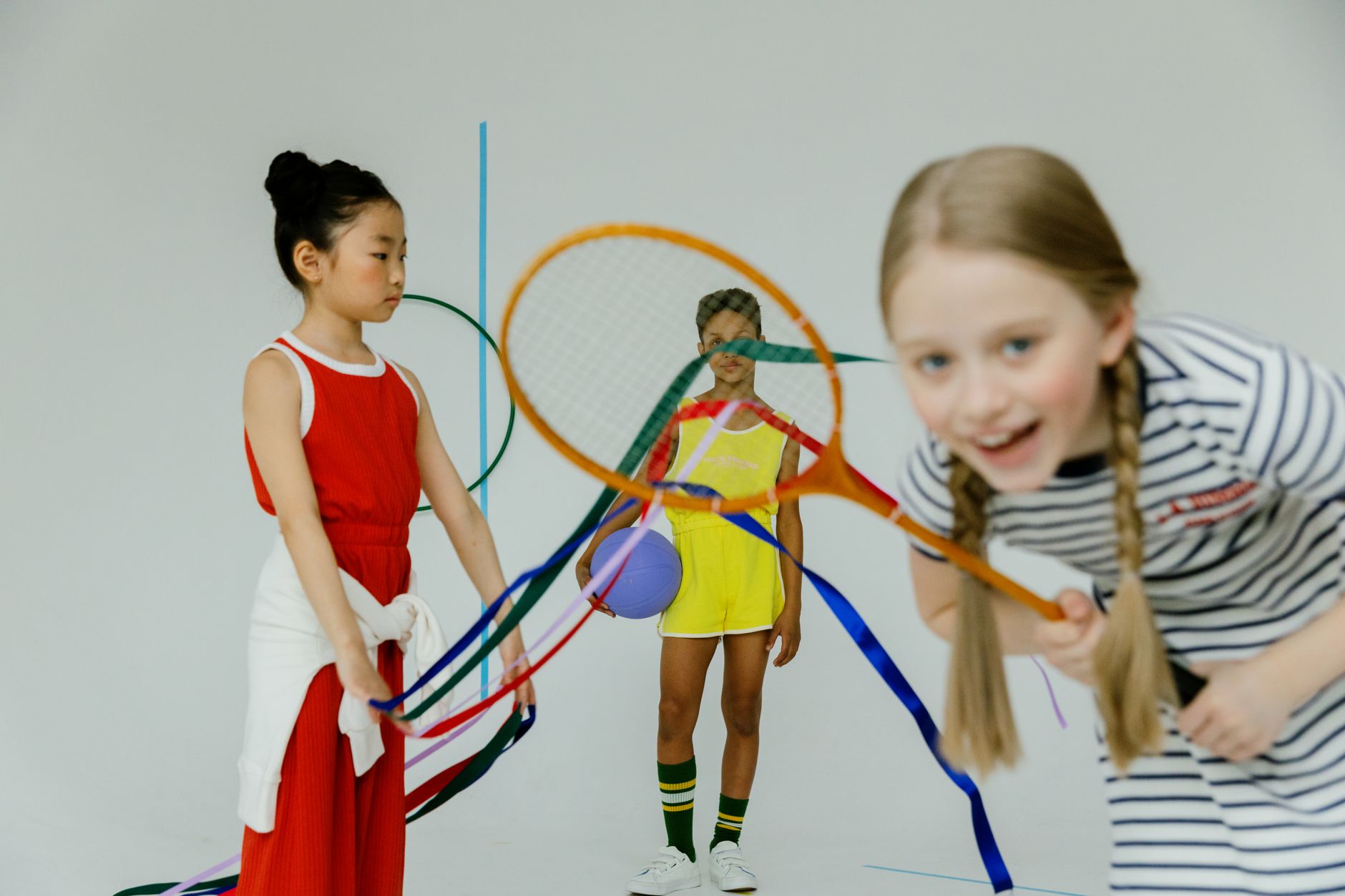 Joyful children having fun with rackets and colorful ribbons indoors.