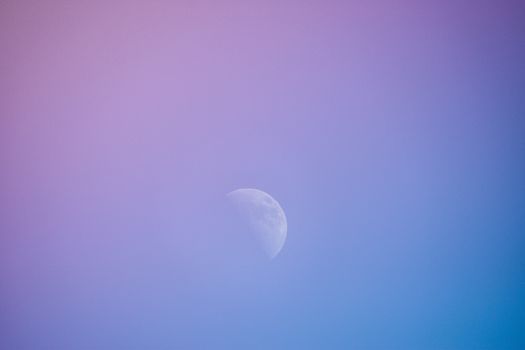 Half moon amid a beautiful gradient sky blending purple and blue hues.
