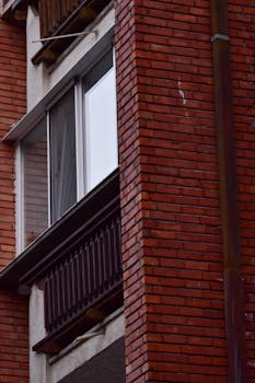 Detailed view of a red brick building facade featuring windows and a vertical drainpipe.