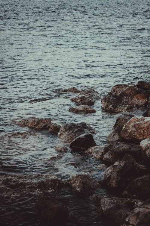 Free Calm ocean waves hitting rocky shore as dusk falls, capturing nature's serenity. Stock Photo