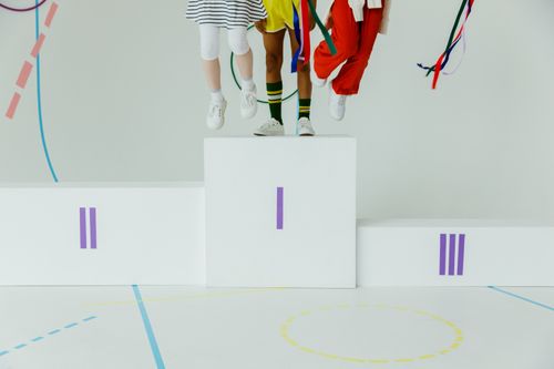 Free Three children jump on a winner's podium, showcasing sports spirit and colorful attire. Stock Photo